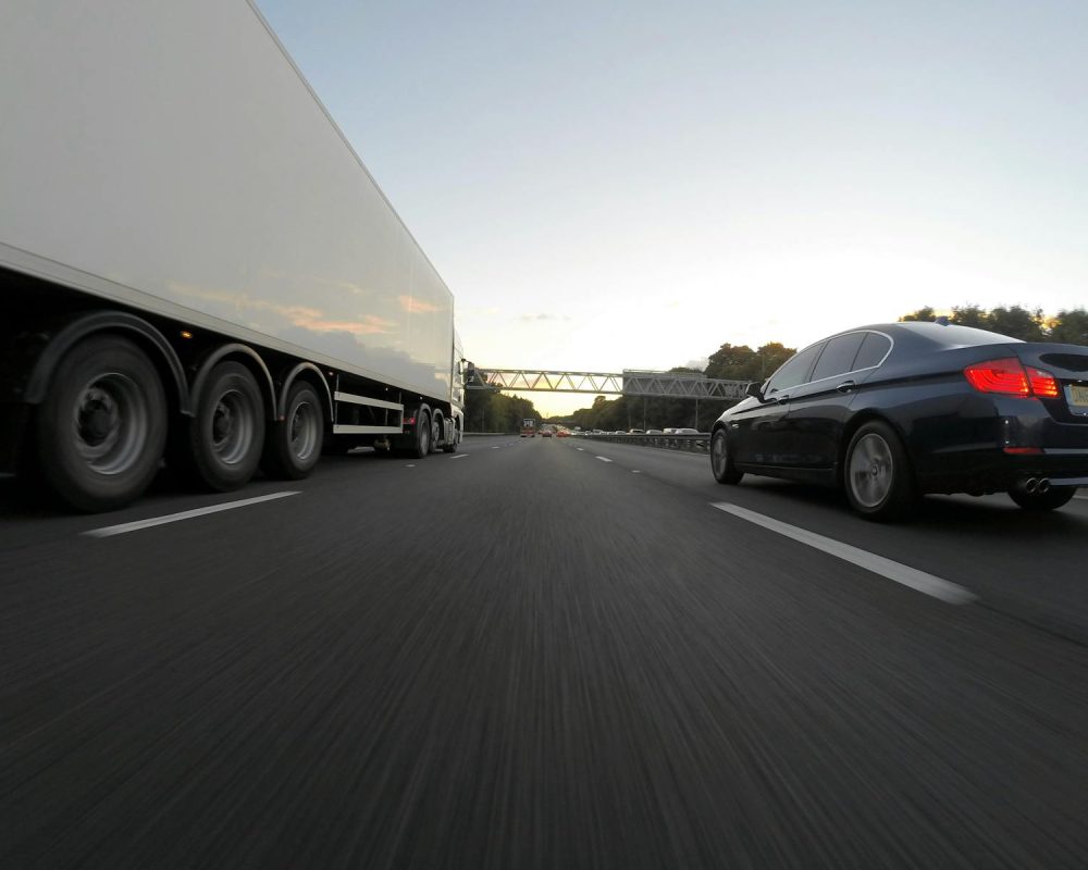 Transporte Santana Carrasco Valdeolmos - Cars and a truck speed along a highway under the clear sky, showcasing transportation dynamics.